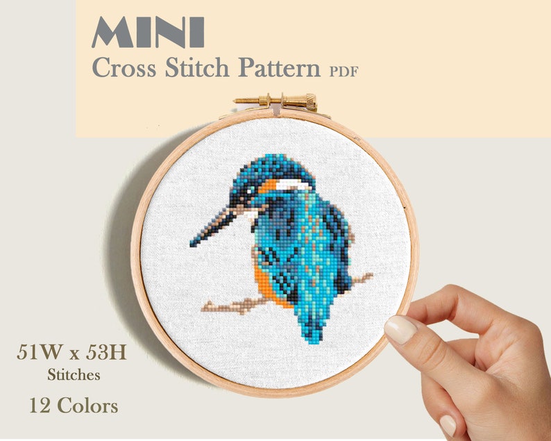 A cross stitch pattern of a blue kingfisher bird on a branch. This is a mini cross stitch pattern.