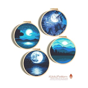 May include: Four round embroidery hoops with blue and white cross stitch patterns of moons and landscapes. The hoops are on a white background.