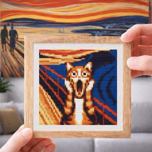 Peut inclure: Une broderie au point de croix encadrée représentant un chat dans le style du "Cri" d'Edvard Munch. L'œuvre présente un chat pixélisé avec une bouche ouverte, sur un fond orange, jaune et bleu vif. Le cadre est en bois clair.