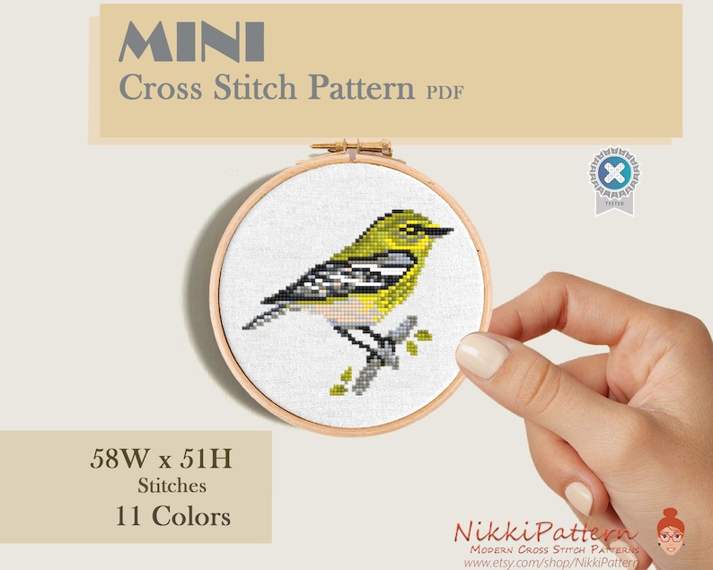 A cross stitch pattern of a yellow and green bird with black markings on a branch. The pattern is mini cross stitch pattern.
