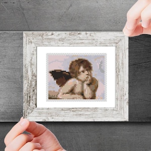 May include: A framed print of a cherub with brown wings, looking thoughtful, in a white frame with a distressed finish.