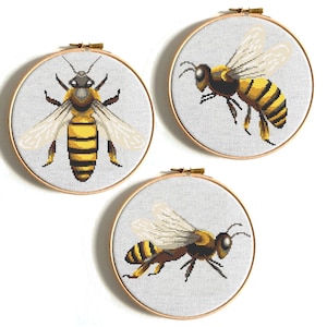 May include: Three embroidery hoop patterns featuring detailed bee illustrations. The bees are depicted in a realistic style with yellow and black stripes, brown eyes, and translucent wings.