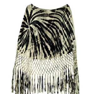 May include: A black and white tie-dye poncho with a crocheted fringe. The poncho has a round neckline and a loose fit.