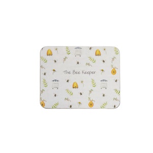 May include: White coaster with a repeating pattern of bees, beehives, and flowers. The text "The Bee Keeper" is printed in the center of the coaster.