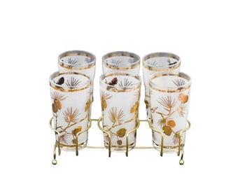 Peut inclure: Ensemble de six verres à pied hauts en verre transparent avec des motifs de pins dorés, présentés sur un support en métal doré.