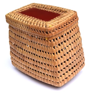 Peut inclure: Un panier en osier tressé avec un couvercle rouge. Le panier est fait de matériaux naturels et a un aspect rustique.