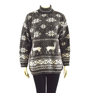 Pode incluir: Um suéter marrom e branco com gola alta e mangas compridas. O suéter apresenta um design de floco de neve e rena.