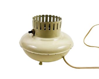 Könnte beinhalten: Ein weißer elektrischer Ventilator mit einem Metallkäfig und einem Kabel. Der Ventilator hat einen runden Sockel und drei Beine.