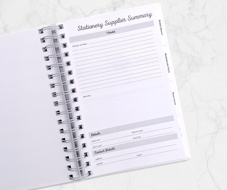 May include: Open white spiral-bound planner with the title "Stationery Supplier Summary" at the top. The planner includes sections for vendor details, order details, sketches, and contact information. Tabs for "Bridal Shower", "Bachelorette Party", and "Honeymoon" are visible.