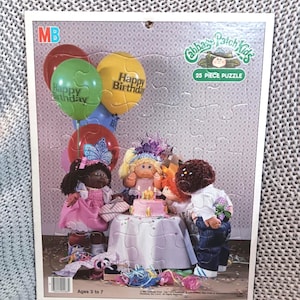 May include: A 25-piece Cabbage Patch Kids puzzle featuring a birthday scene. The puzzle shows Cabbage Patch Kids dolls around a cake, with balloons that say "Happy Birthday." The puzzle is for ages 3 to 7.
