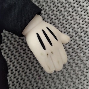 May include: A white plush glove with black stitching, resembling a cartoon character's hand.