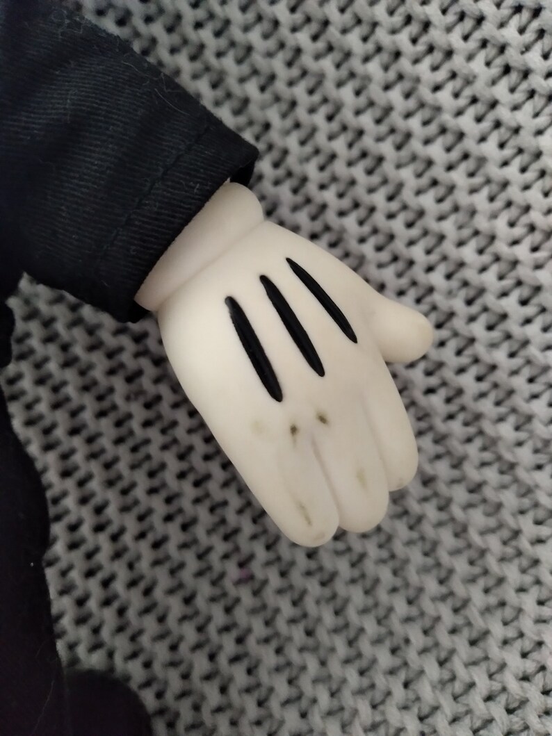 May include: A white plush glove with black stitching, resembling a cartoon character's hand.