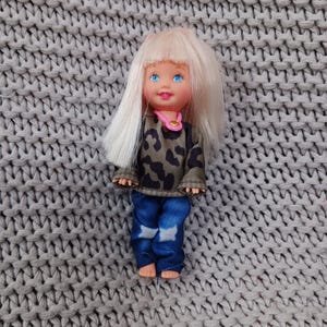 Barbie&#39;s littlest sister Kelly in camo top, blue jeans, and a choker necklace