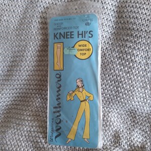 May include: A package of sheer knee-high stockings with a reinforced toe. The package is blue and white and features a woman wearing a yellow jumpsuit. The text on the package reads "Worthmore" and "Knee Hi's".