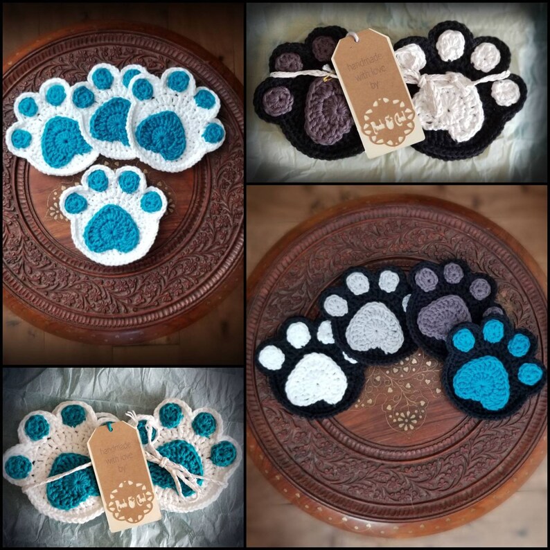 May include: Set of crocheted paw print coasters in various colors, including white, gray, black, and blue. The coasters are handmade and feature a tag that reads "Handmade with love by Paw & Co."