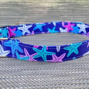 May include: A blue dog collar with a white, pink, and turquoise starfish pattern.