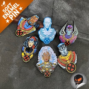 Puede incluir: Conjunto de siete pines de esmalte con personajes de la serie de cómics X-Men. Los pines son coloridos y presentan ilustraciones detalladas de las caras y los trajes de los personajes. Los pines están etiquetados como "Soft Enamel Pin" en la esquina superior izquierda.