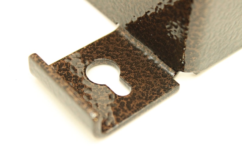 May include: Close-up of a metal keyhole cover with a textured, brown finish. The keyhole is visible in the centre of the cover.