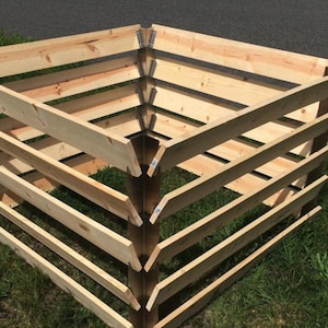 May include: A wooden compost bin with four sections, each with a slatted design. The bin is made of natural wood and has metal corner brackets.