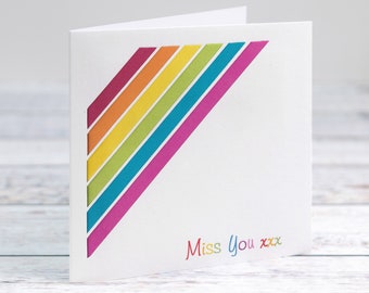 May include: A white card with a rainbow design and the text "Miss You xxx" in colorful letters.