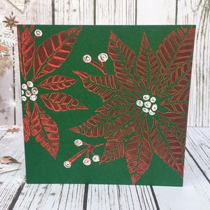 Tarjeta navideña con impresión en linóleo de flor de Pascua roja y detalles dorados pintados a mano sobre cartulina marrón o cartulina verde. Saludos festivos de temporada