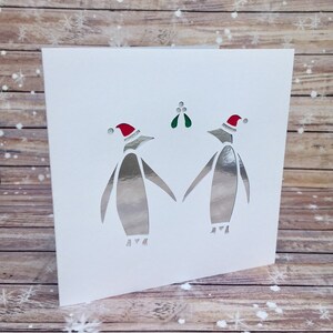 Couple de pingouins avec chapeaux de fête et carte de Noël de gui - Une carte spéciale pour votre proche à Noël - Fiançailles de mariage