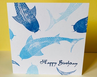 May include: A white card with a blue and white fish design and the text "Happy Birthday".