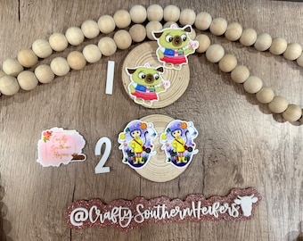 May include: A set of four colorful, hand-painted resin ornaments featuring characters from popular children's movies. The ornaments are displayed on a wooden surface with a wooden bead garland and a sign that reads "Crafty Southern Heifers".