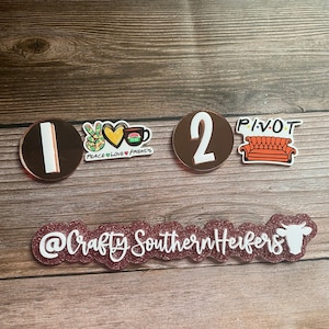 May include: A set of five acrylic stickers with a pink glitter background. The stickers feature the numbers 1 and 2, a peace sign with a heart and a coffee cup, a couch with the word "PIVOT" above it, and the text "@CraftySouthernHeifers" with a cow silhouette.