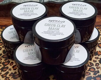 Może przedstawiać: Sześć małych czarnych słoiczków z zieloną glinką do twarzy z białymi etykietami, na których widnieje napis "Wellca Detoxifying Green Clay Mask" i lista składników.
