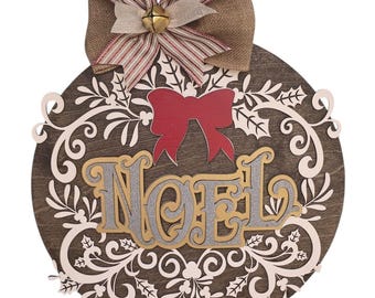 May include: A round wooden Christmas ornament with the word "NOEL" in gold and silver glitter. The ornament has a white floral design and a red bow. A burlap bow with a small gold bell is at the top.