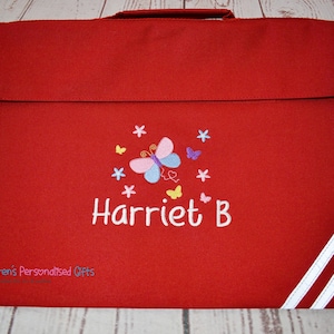 Puede incluir: Mochila roja con correas blancas y un dise&ntilde;o de mariposa bordado en la parte delantera. La mochila est&aacute; personalizada con el nombre "Harriet B."