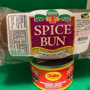 Puede incluir: Un paquete de Spice Bun, un producto horneado jamaicano, con una etiqueta que dice "Great Taste! Made with Real Fruit!" y una lata de Tastee Pasteurized Processed Cheese Spread. El pan pesa 340g.