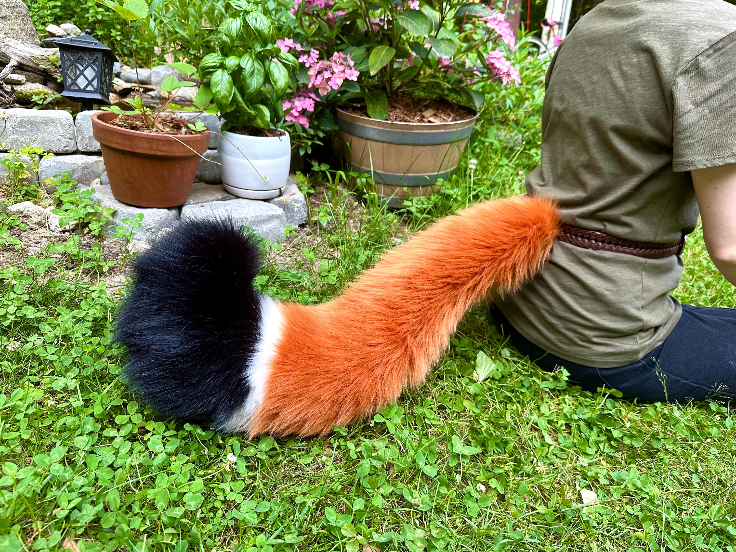 ふわふわの三色キツネのしっぽ - ぬいぐるみの毛皮のようなキツネの獣