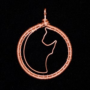 May include: A copper wire pendant in the shape of a circle with a silhouette of a stylized animal inside. The pendant has a loop at the top for hanging.