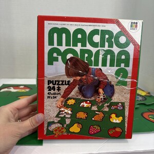 May include: A vintage "Macro Forma 2" puzzle box with a red border and green lettering. The box features a child playing with the puzzle pieces, which depict farm animals and fruits. The puzzle measures 19 x 24 inches.