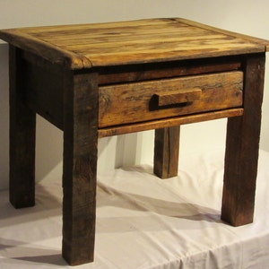 Könnte beinhalten: Ein rustikaler Holz-Beistelltisch mit einer Schublade und vier Beinen. Der Tisch ist aus recyceltem Holz gefertigt und hat eine natürliche Oberfläche.