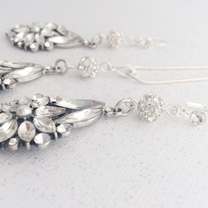 May include: A silver necklace and earrings set with crystal and pearl accents. The necklace features a round crystal pendant and the earrings have a teardrop shape.
