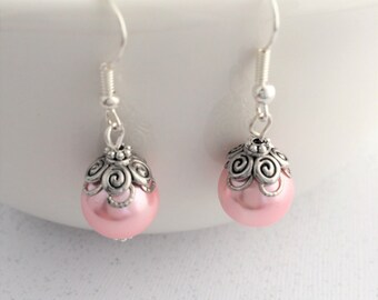 Puede incluir: Un par de pendientes de plata con cuentas de color rosa perla y un diseño de filigrana de plata.