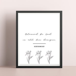 Può includere: Arte da parete stampabile in bianco e nero con la citazione "Benedetto sia Dio in tutte le sue opere." di Beato Solanus Casey. La citazione è circondata da tre fiori di iris stilizzati.