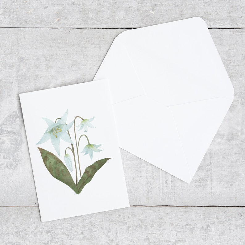 White Lily botanical watercolor painting printed onto a white card. Image is centred on a white cardstock background. White envelope rests below the card.