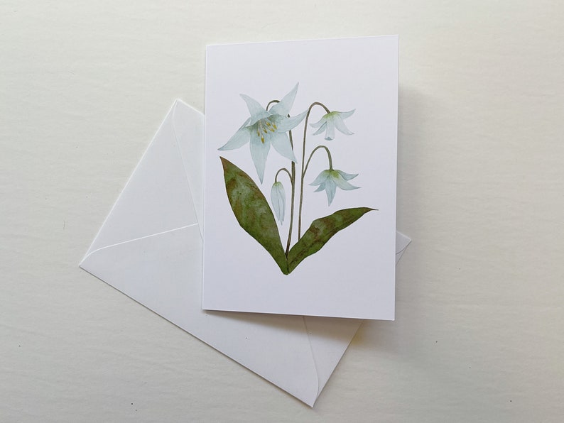 White Lily botanical watercolor painting printed onto a white card. Image is centred on a white cardstock background. White envelope rests below the card.