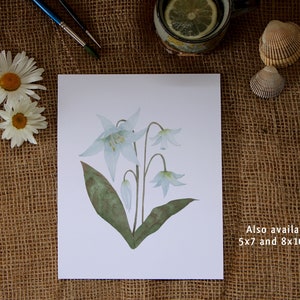 White lily botanical watercolour painting is also available as an art print. Flat lay of print on a burlap brown table cover.