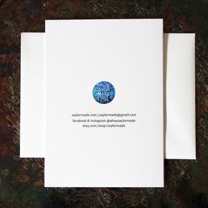 The back of the card displays the artists logo SaylorMade as well as social media and website contact information. These items are small in size and printed centred on the back.