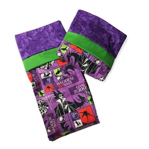 May include: Two purple and green fabric pillowcases with a Maleficent theme. The pillowcases feature a repeating pattern of Maleficent, dragons, spiders, skulls, and the text "The Baddest Bad".
