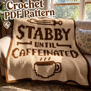 Pode incluir: Um cobertor de crochê creme com letras marrons que diz "STABBY UNTIL CAFFEINATED" e um gráfico de xícara de café. O cobertor tem uma borda marrom e está sobre um sofá. As palavras "Crochet PDF Pattern" estão no topo.