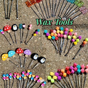 May include: A collection of wax tools with decorative tops, including hearts, bears, mushrooms, penguins, and dice. The tools are arranged on a textured surface, with the words "Wax Tools" in green script. The tools come in various colors.