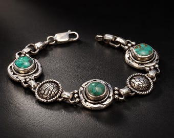 May include: A silver link bracelet featuring three round turquoise cabochons and two circular silver medallions with embossed floral patterns. The bracelet is secured with a lobster claw clasp and has a polished, oxidized finish.