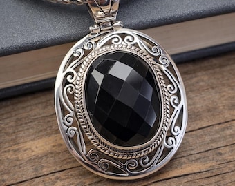 May include: A sterling silver pendant featuring a large, oval, faceted black gemstone set within an intricate, openwork filigree frame. The pendant hangs from a thick, woven silver chain, showcasing detailed metalwork and a polished finish.