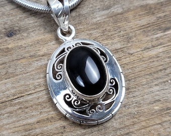 May include: A silver pendant necklace with a black oval gemstone set in a detailed silver frame. The pendant hangs from a silver snake chain.